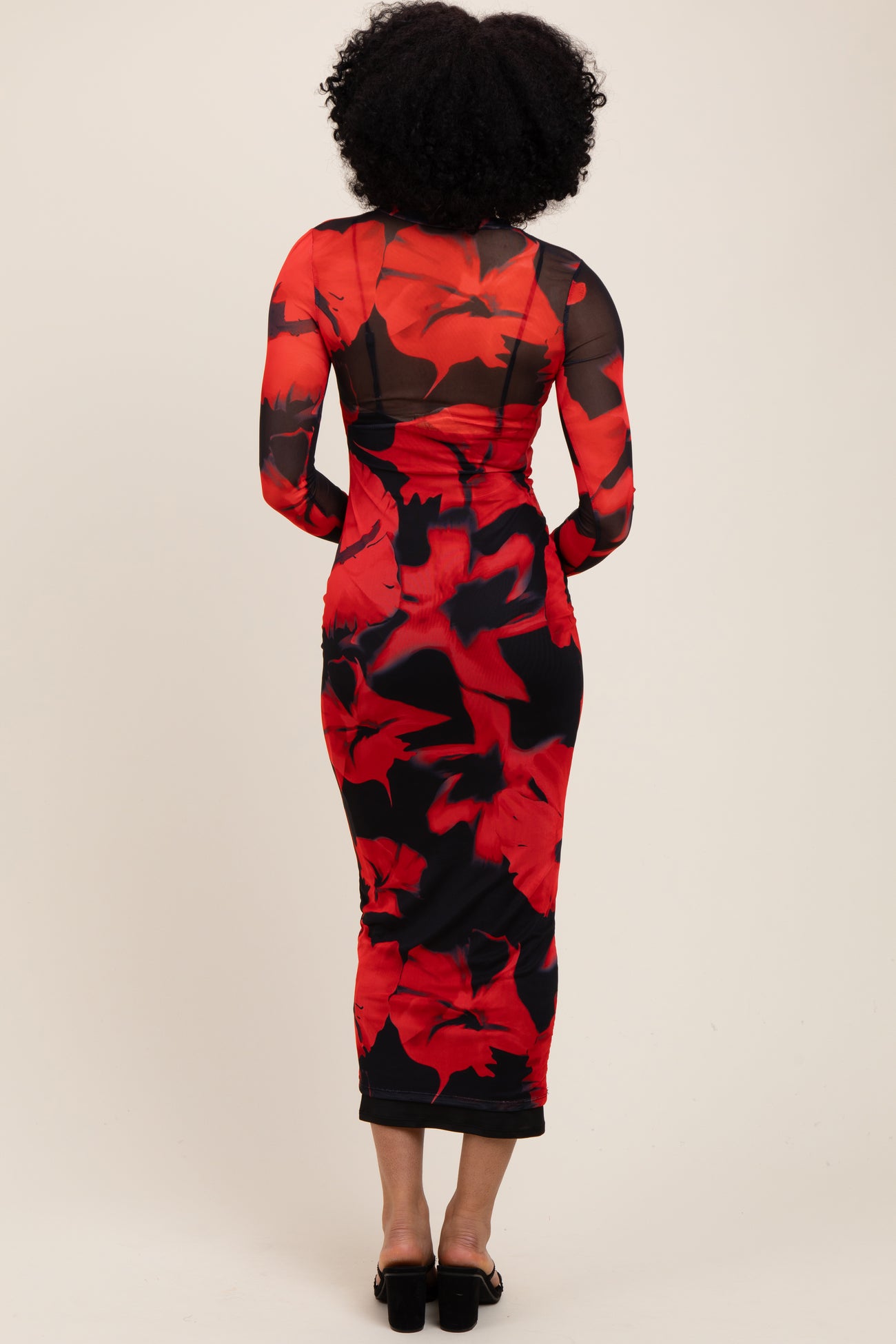 woman wearing a red floral midi dress with long sheer sleeves and a fitted silhouette, view from the back