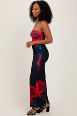 woman wearing a strapless floral maxi dress with red roses and a side slit, styled with black heeled sandals