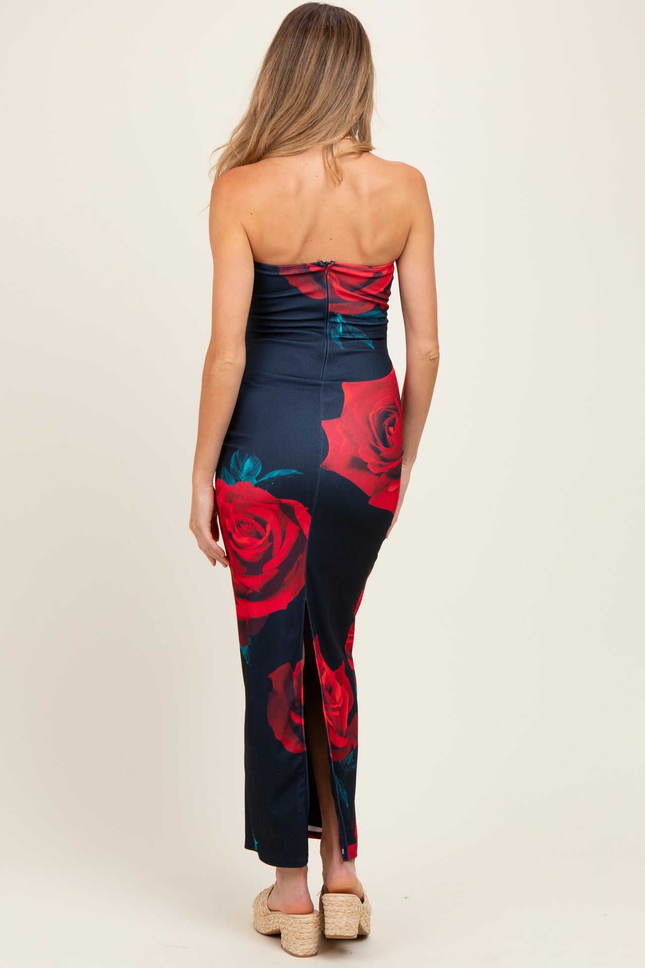 woman wearing a navy strapless maternity dress with red rose print and a slit at the back