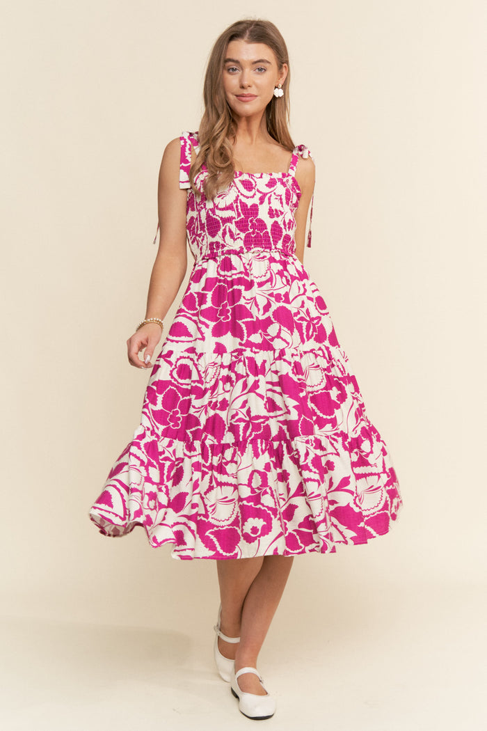woman wearing a pink floral midi dress with tie straps and a tiered skirt