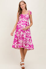 woman wearing a pink floral maternity dress with tie straps and a visible baby bump