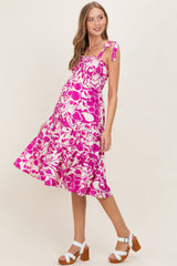 woman wearing a pink and white floral maternity dress with tie straps and a flowing skirt, showing her baby bump