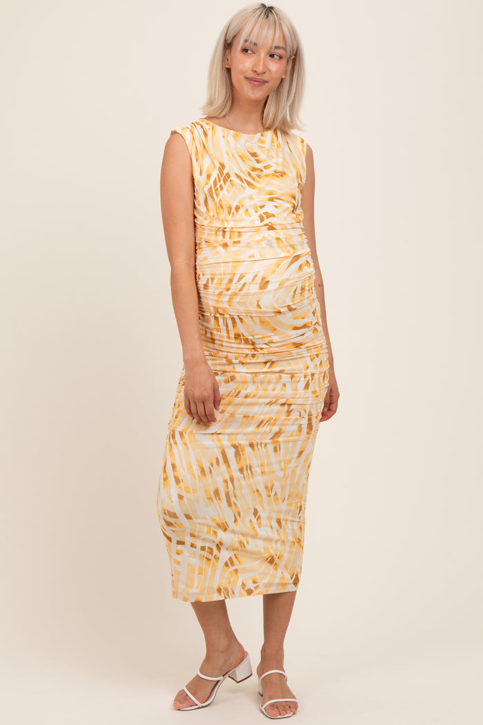 woman wearing a yellow and white patterned maternity midi dress with ruching and a visible baby bump