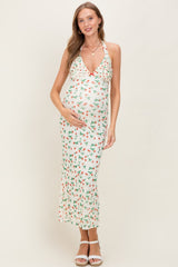 woman wearing a floral print maternity dress with a ruffled neckline and a baby bump, standing and smiling