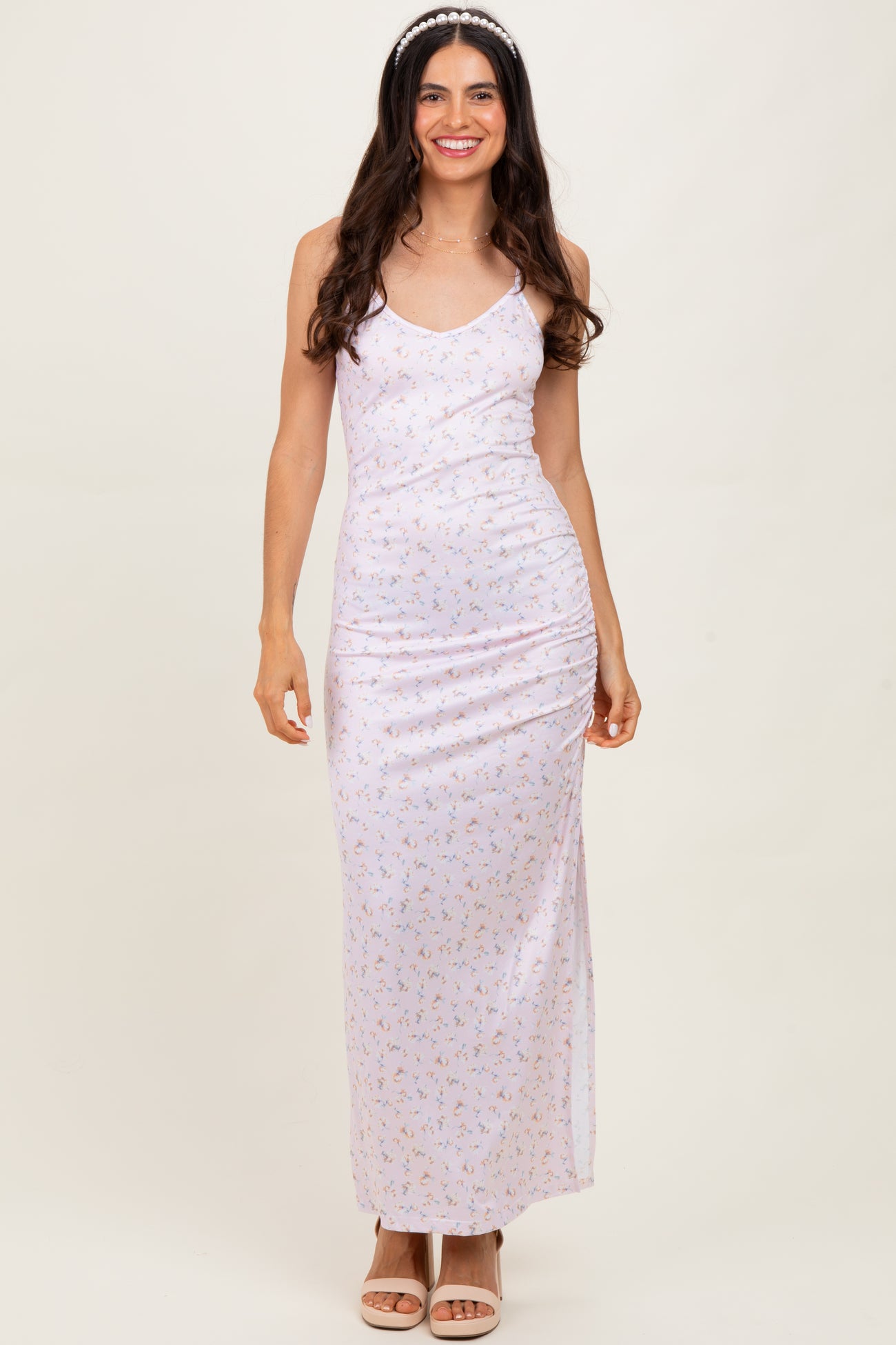 woman wearing a light pink floral maxi dress with spaghetti straps and a fitted silhouette