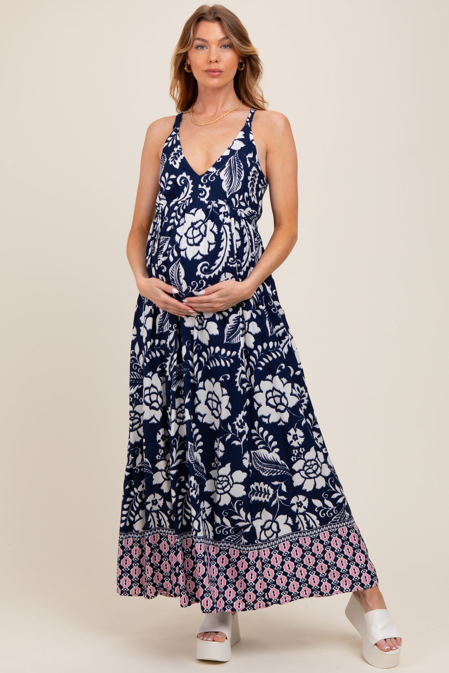 woman wearing a navy blue maternity maxi dress with floral patterns and a visible baby bump