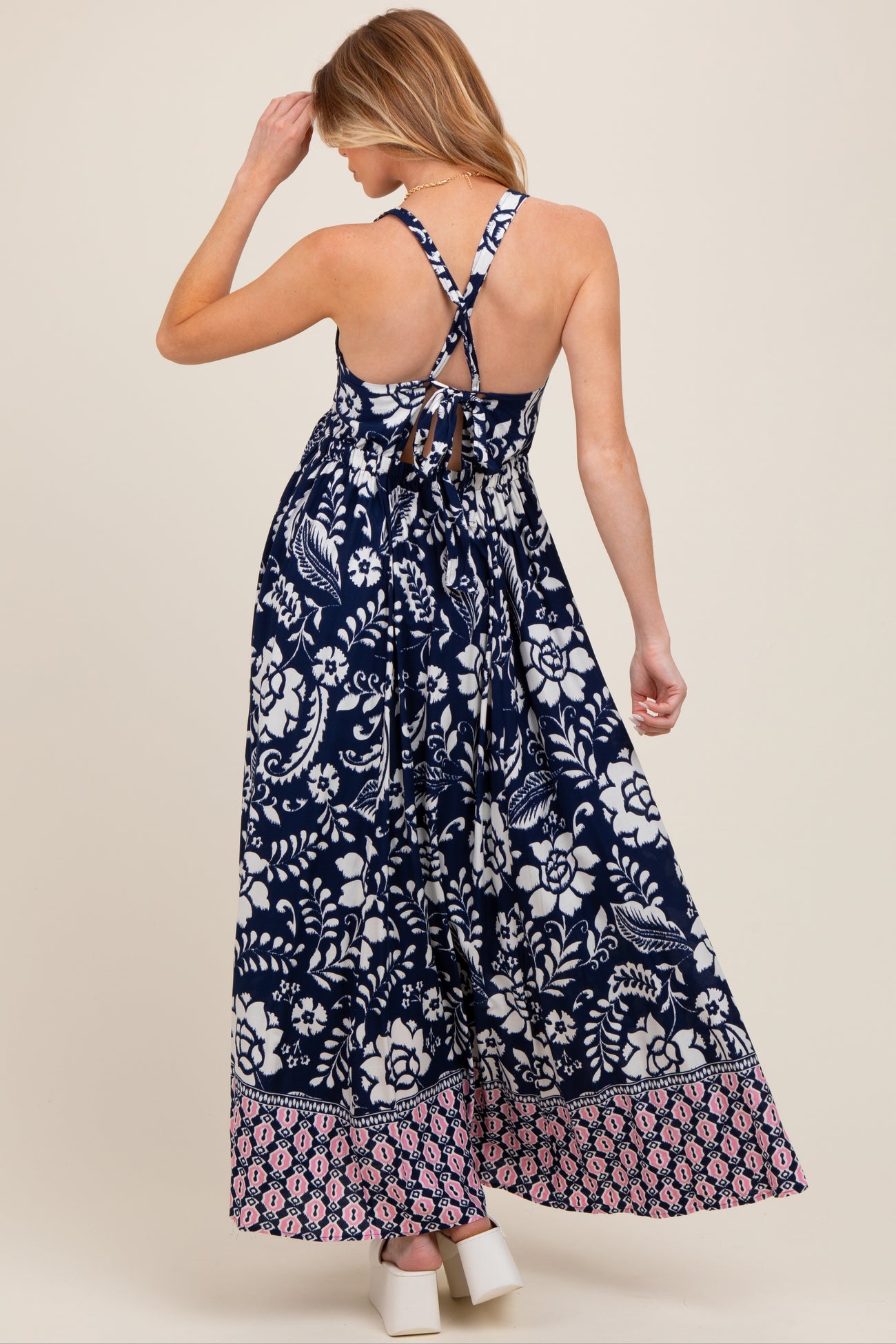 woman wearing a navy blue floral print maternity maxi dress with crisscross back straps and a flowy silhouette