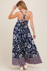 woman wearing a navy blue floral print maternity maxi dress with crisscross back straps and a flowy silhouette