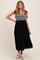 woman wearing a black maternity dress with embroidered bodice and tie straps, featuring a flowy tiered skirt