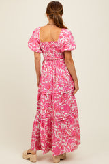 woman wearing a pink floral maxi dress with puff sleeves and a tiered skirt, photographed from the back