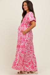 woman wearing a pink floral print maternity maxi dress with puff sleeves and pockets, showing her baby bump