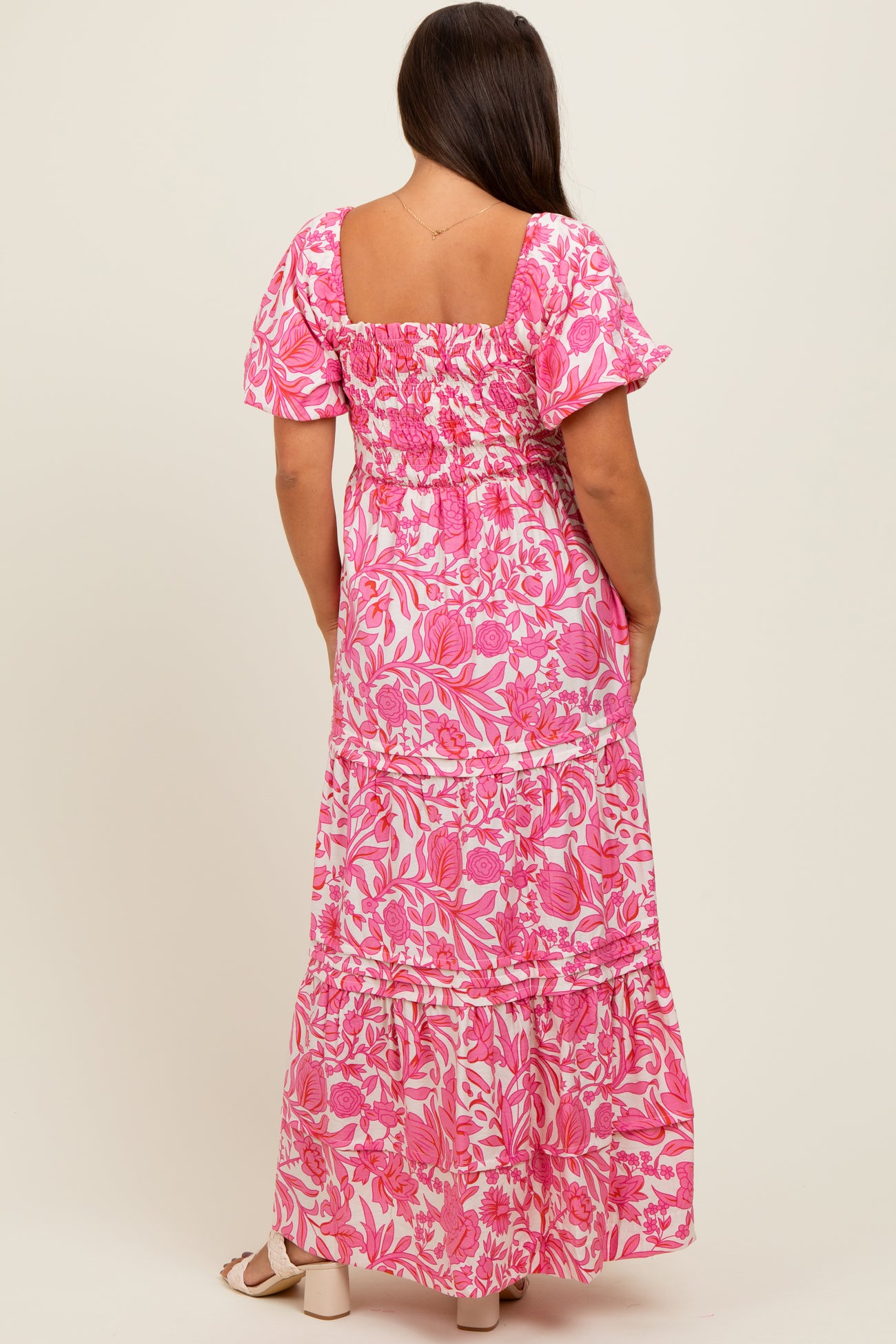 woman wearing a pink floral maternity maxi dress with puff sleeves and a smocked back detail