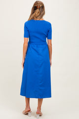 woman wearing a cobalt blue maternity dress with a fitted top and flowy skirt, seen from behind
