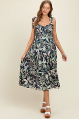 woman wearing a navy blue floral maternity maxi dress with tie shoulder straps and a tiered skirt