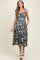 woman wearing a dark floral print maternity dress with tie shoulder straps and pockets, showing her baby bump