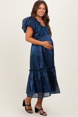 woman wearing a navy blue satin maternity dress with puff sleeves and a flowy skirt, cradling her baby bump