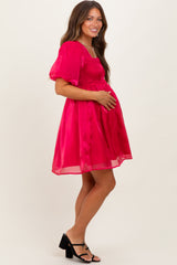 woman wearing a bright pink maternity dress with puff sleeves and a smocked bodice, holding her baby bump