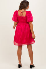 woman wearing a pink maternity dress with puff sleeves and a smocked back, showing a flowy silhouette
