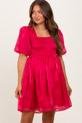 woman wearing a bright pink puff sleeve maternity dress with a smocked bodice and flowy skirt