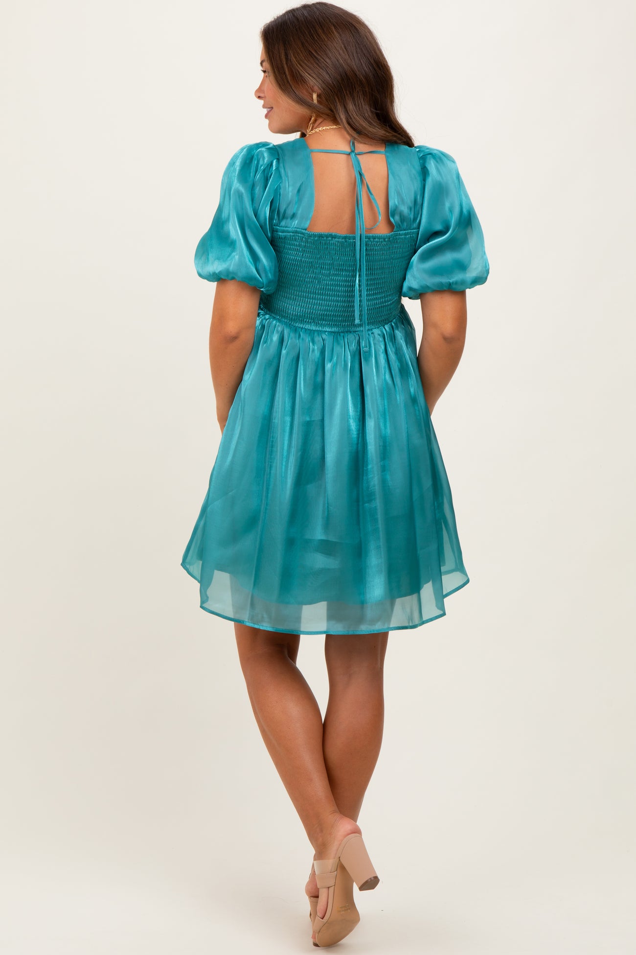 woman wearing a teal maternity dress with puff sleeves and smocked back, showcasing a flowy skirt