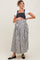woman wearing a black and white striped maternity dress with denim overalls and holding her baby bump