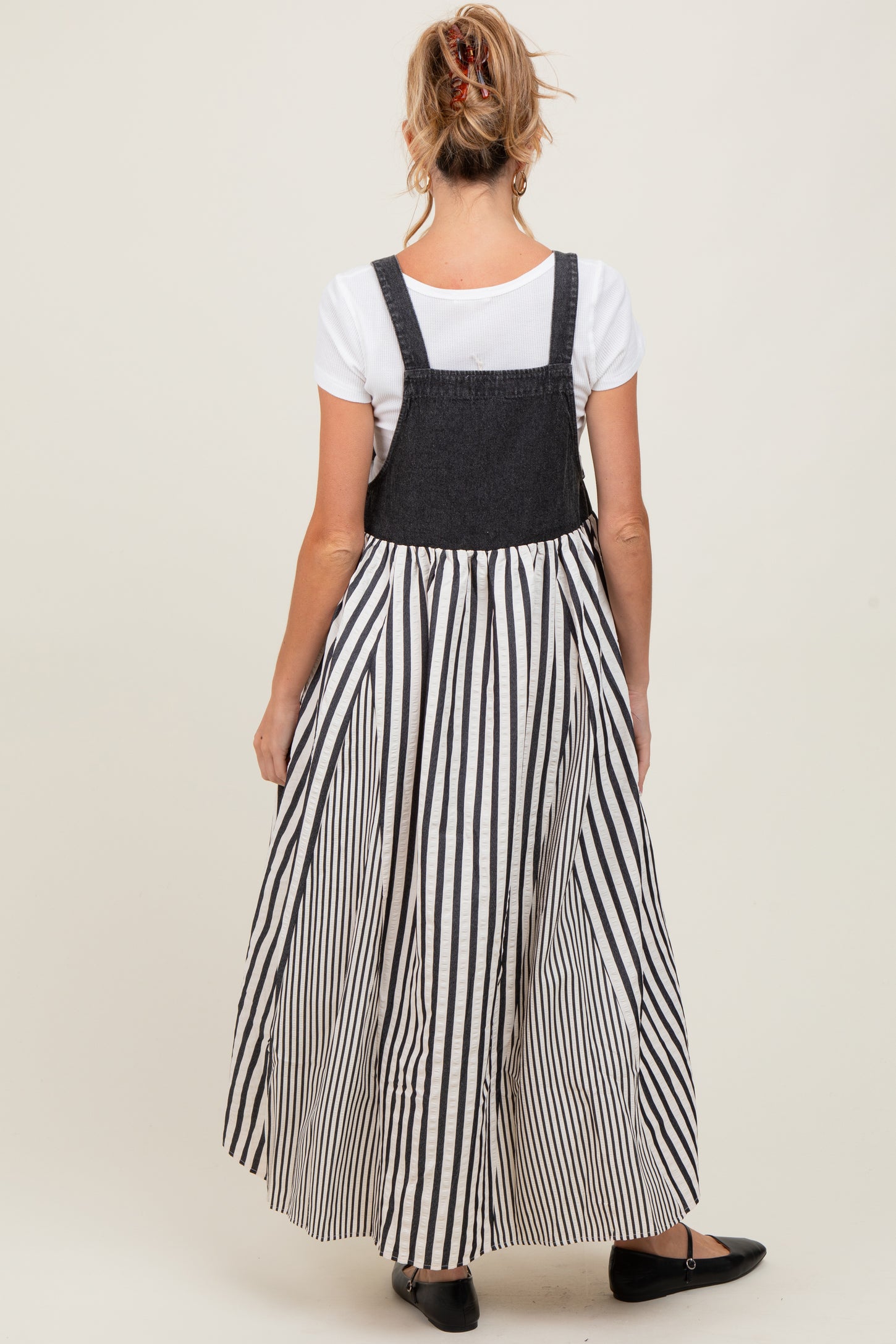 woman wearing a black and white striped maternity maxi dress with a denim top and back, showing off her baby bump