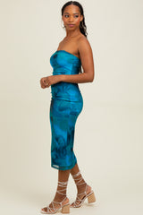 woman wearing a strapless teal floral midi dress and strappy beige heels, standing sideways with a neutral background