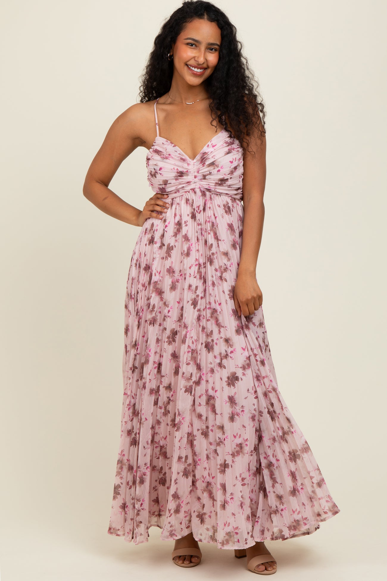 woman wearing a pink floral maxi dress with a deep v-neckline and spaghetti straps