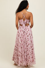 woman wearing a backless pink floral maxi dress with a tie detail and spaghetti straps