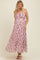 woman wearing a pink floral maternity maxi dress with a pleated design and a fitted bodice, showing her baby bump