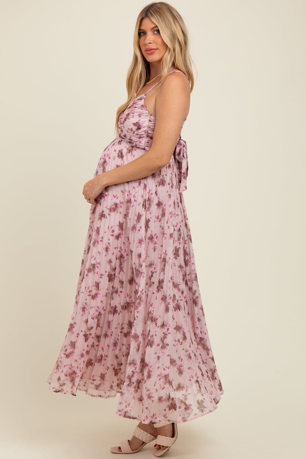 woman wearing a pink floral maternity maxi dress with a tie-back detail and showcasing her baby bump