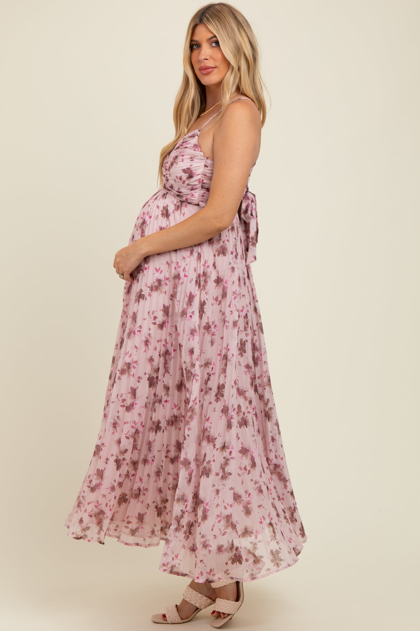 woman wearing a pink floral maternity maxi dress with a tie-back detail and showcasing her baby bump
