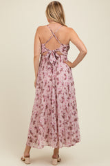 woman wearing a pink floral maternity maxi dress with a crisscross back detail and bow accent