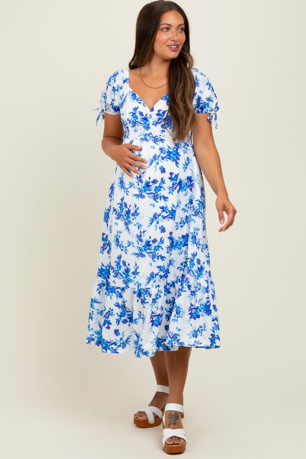 woman wearing a blue and white floral maternity dress with short sleeves and a visible baby bump