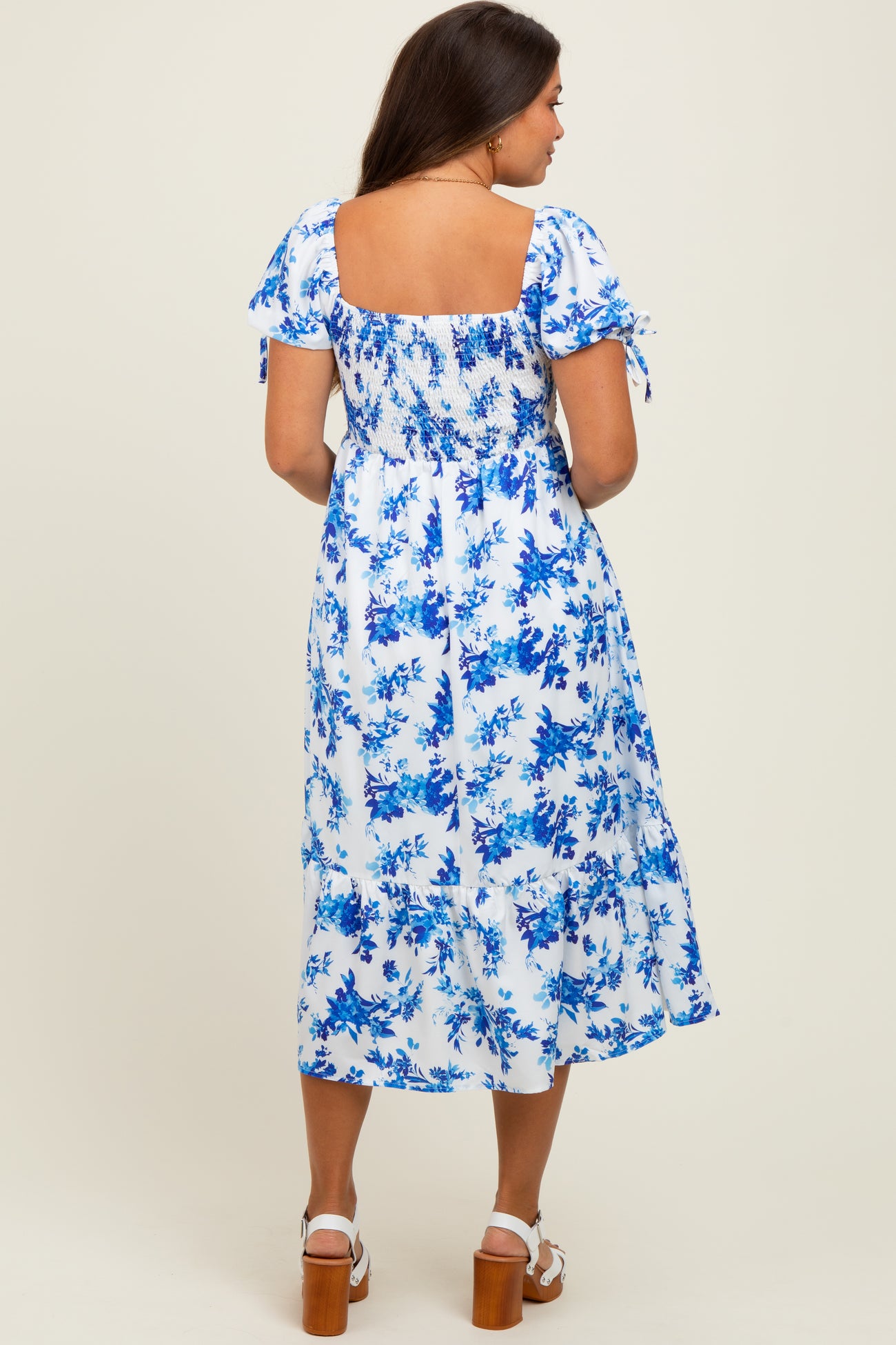 woman wearing a blue and white floral smock maternity dress with short puff sleeves and a tiered hemline