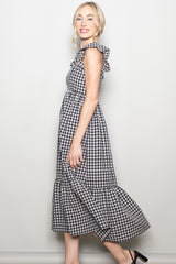 woman wearing a black and white gingham maxi dress with ruffle details and a tiered skirt