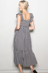 woman wearing a black and white gingham print midi dress with puff sleeves and a tiered hem