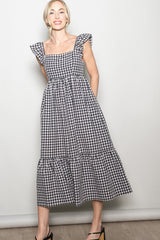 woman wearing a black and white gingham midi dress with ruffle sleeves and a tiered skirt