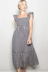 woman wearing a black and white gingham maxi dress with ruffle sleeves and a tiered skirt