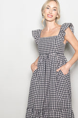 woman wearing a black and white gingham dress with ruffle sleeves and side pockets