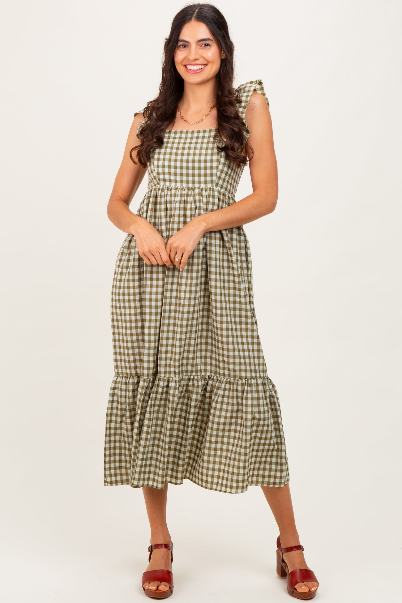 woman wearing a green and white gingham midi dress with a ruffled hem and shoulder straps