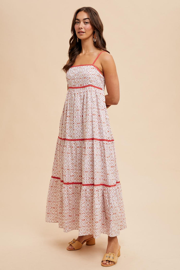 woman wearing a white maxi dress with red geometric patterns and adjustable straps