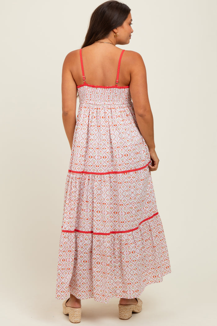 woman wearing a patterned white and pink maternity maxi dress with smocked back and tiered skirt, showing her baby bump