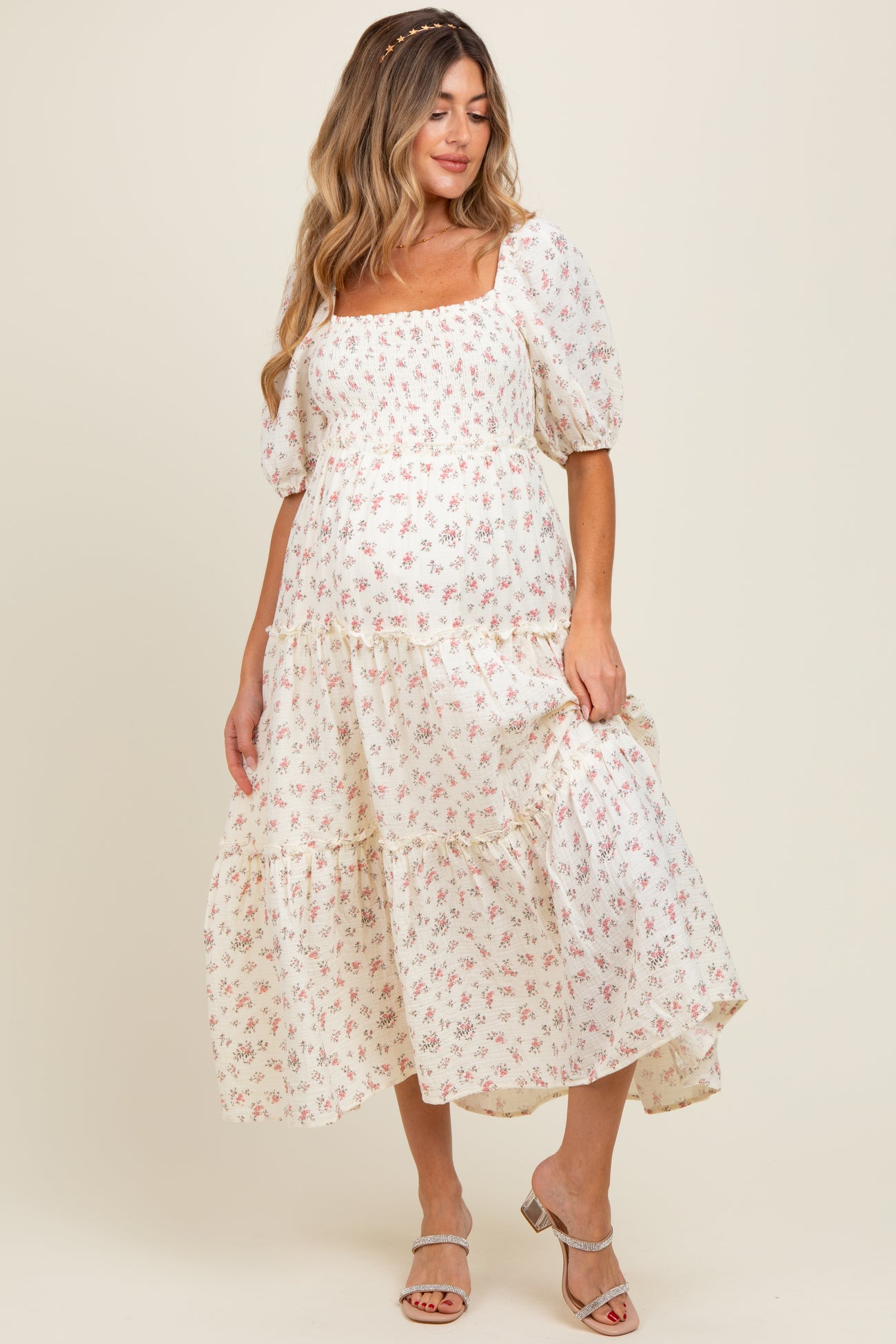 woman wearing a white floral maternity maxi dress with puff sleeves and a fitted bodice, showcasing a baby bump