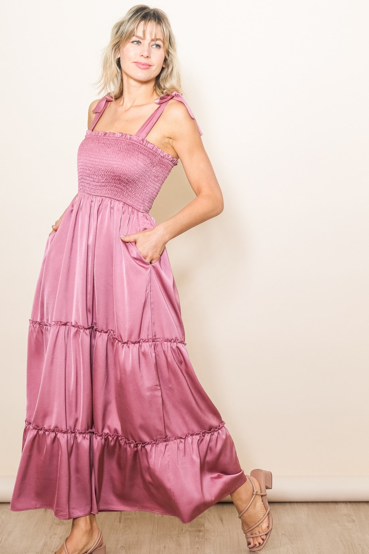 woman wearing a pink tiered maxi dress with smocked bodice and tie shoulder straps, featuring pockets