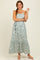 woman wearing a light green floral print maxi dress with tiered skirt and adjustable straps