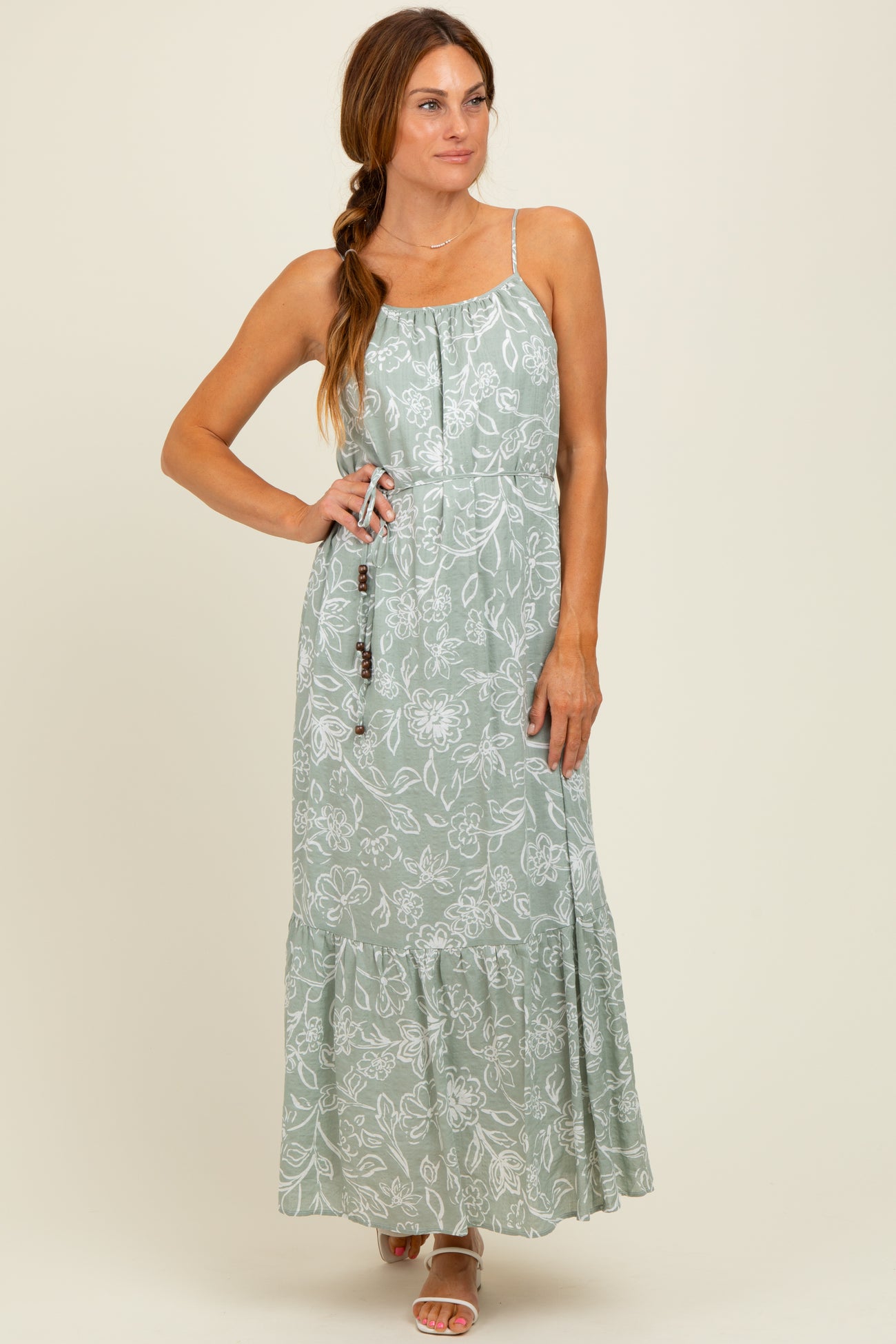 woman wearing a green floral maxi dress with adjustable straps and a ruffled hem