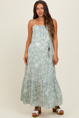 woman wearing a light green floral maternity maxi dress with adjustable straps and a tiered skirt