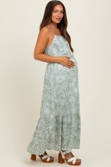 woman wearing a green floral print maternity maxi dress and showing her baby bump