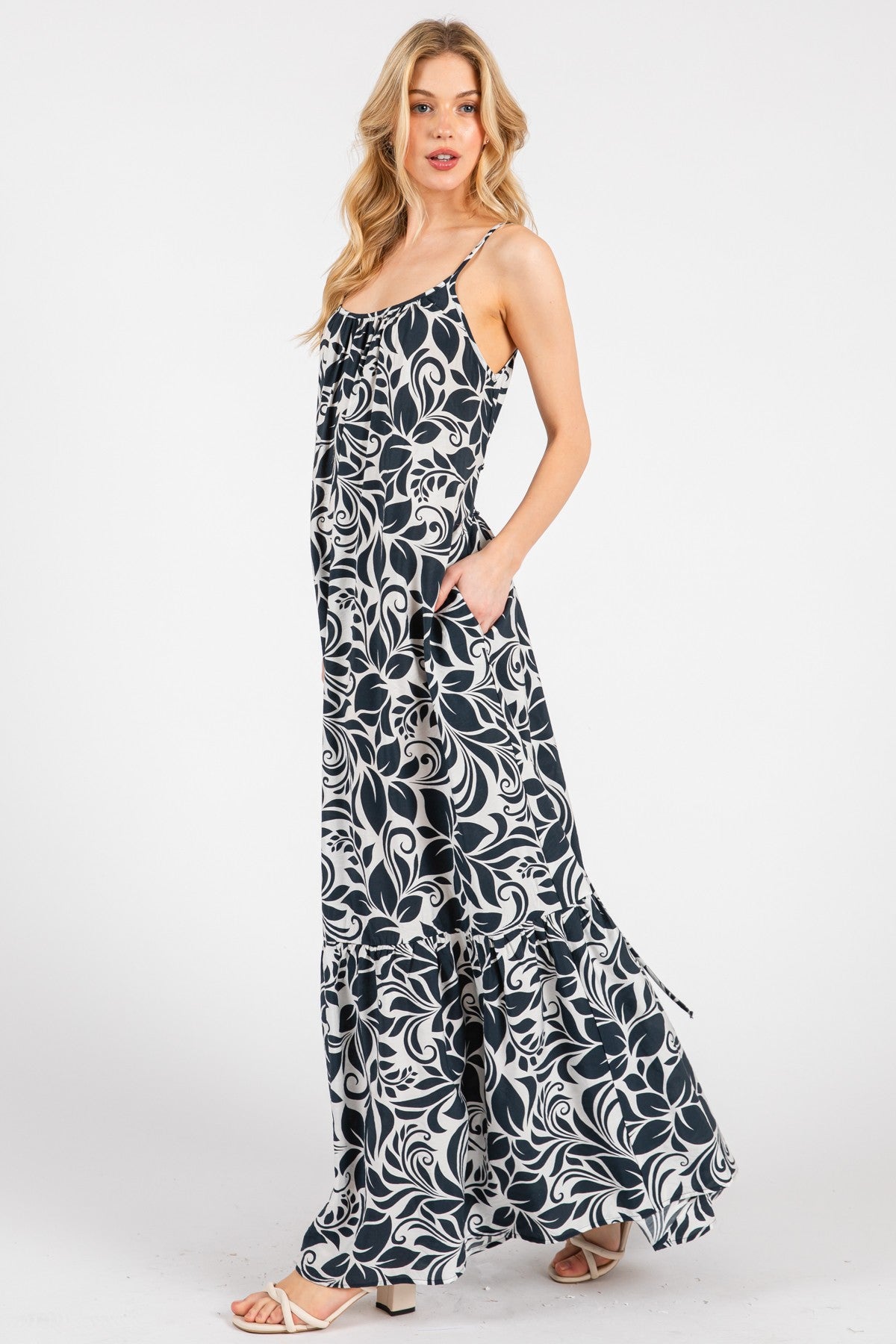 woman wearing a navy and white floral maxi dress with adjustable straps and pockets
